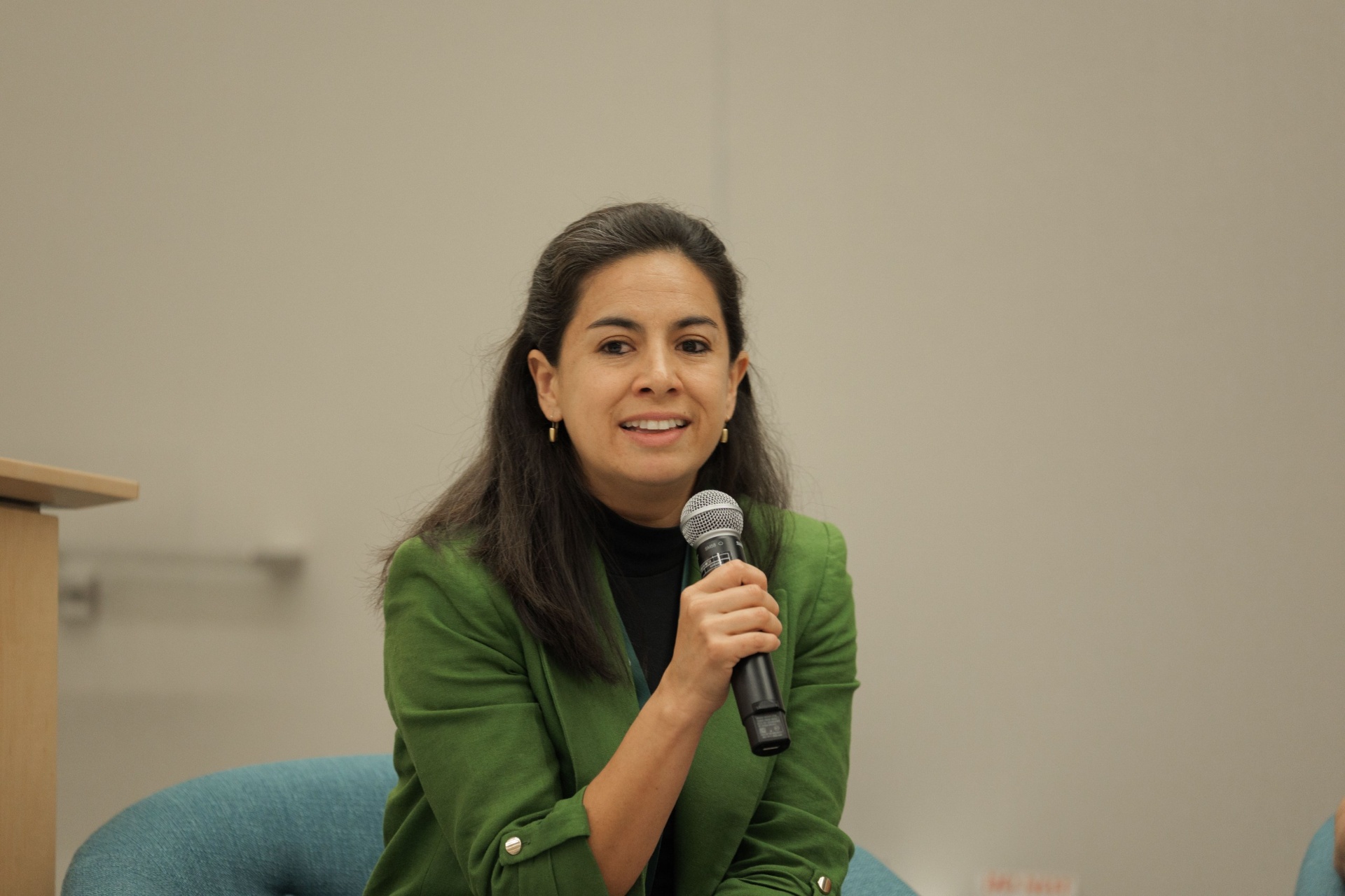 Capital Day moderator in green blazer smiling while leading the founders and investors panel
