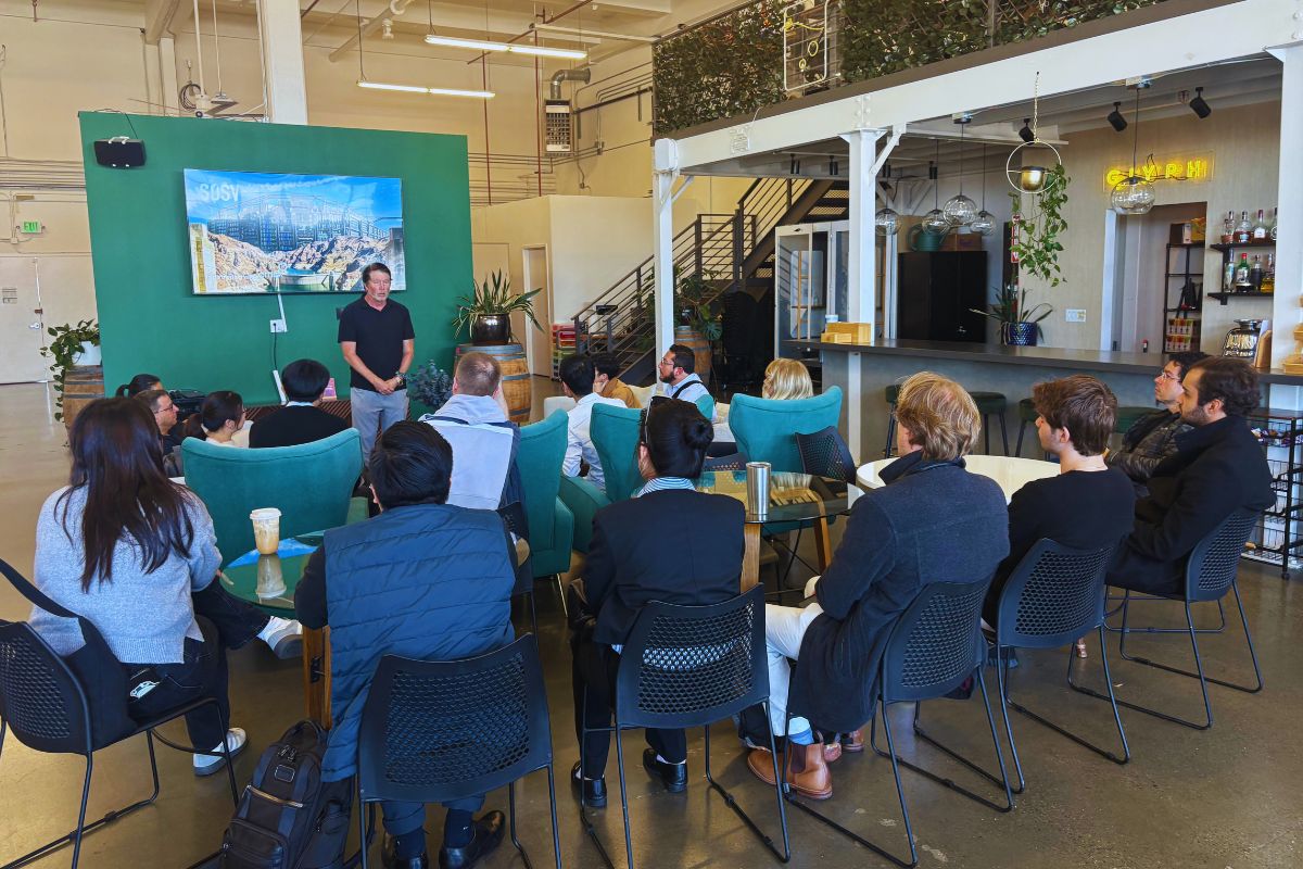 Frontiers Day audience seen from behind listening to the SOSV host in front of the green backdrop with the SOSV Hoover Dam image