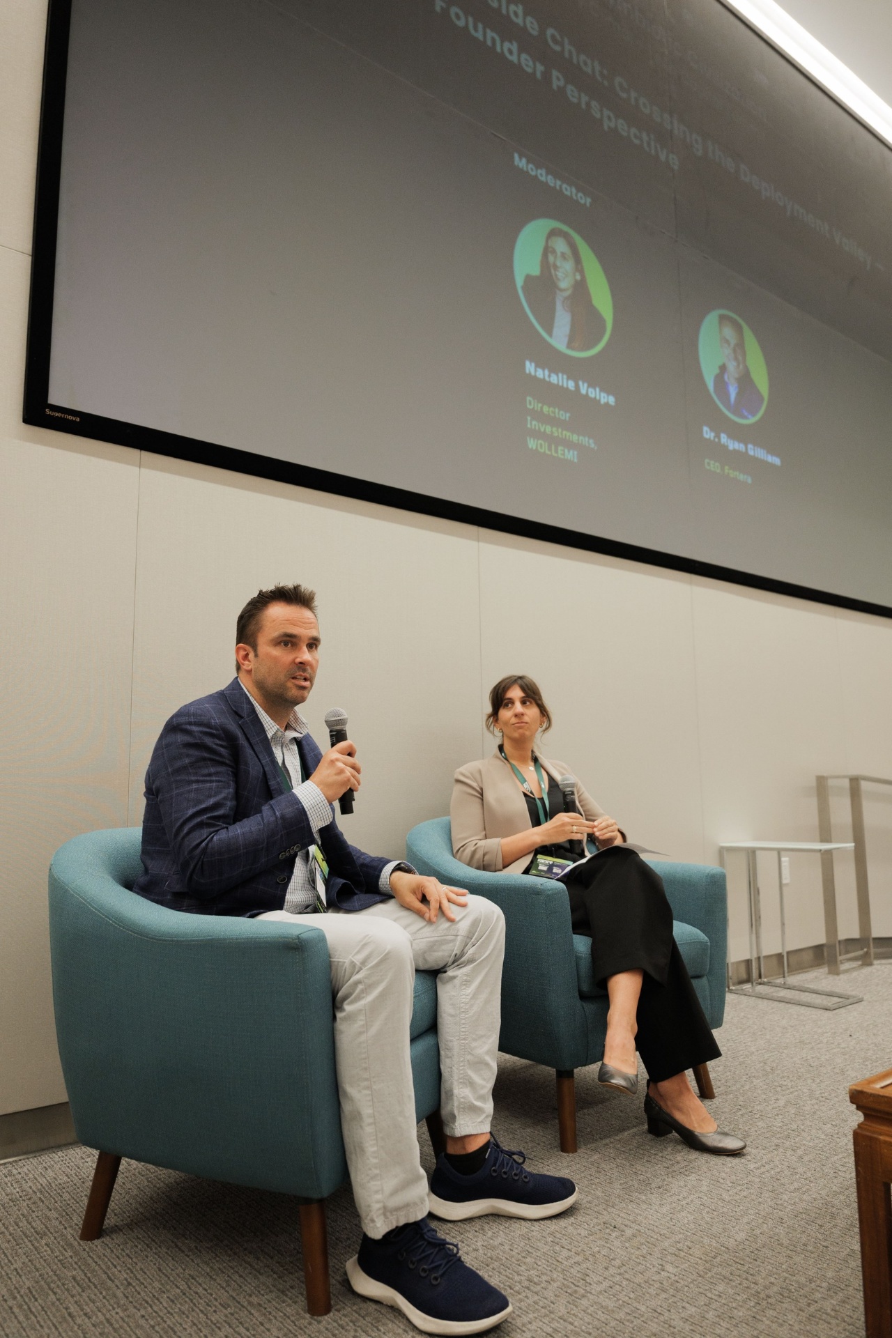 Capital Day fireside chat 'Crossing the Deployment Valley — Founder Perspective' at UC Law SF — Dr. Ryan Gilliam, CEO of Fortera, speaking beside moderator Natalie Volpe, Director of Investments at WOLLEMI, beneath the session title slide