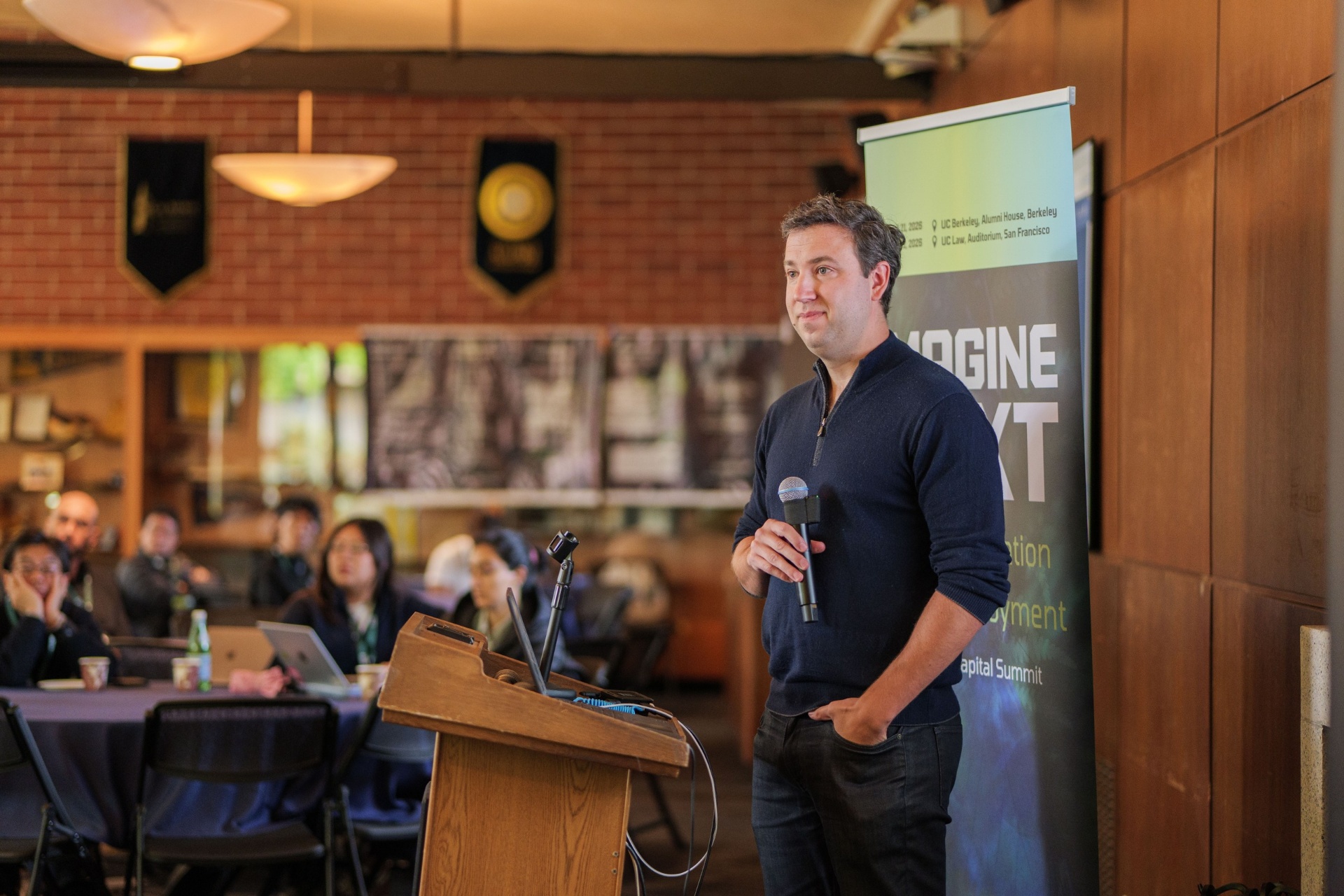 Master the Model speaker presenting from the podium beside the Imagine Next banner