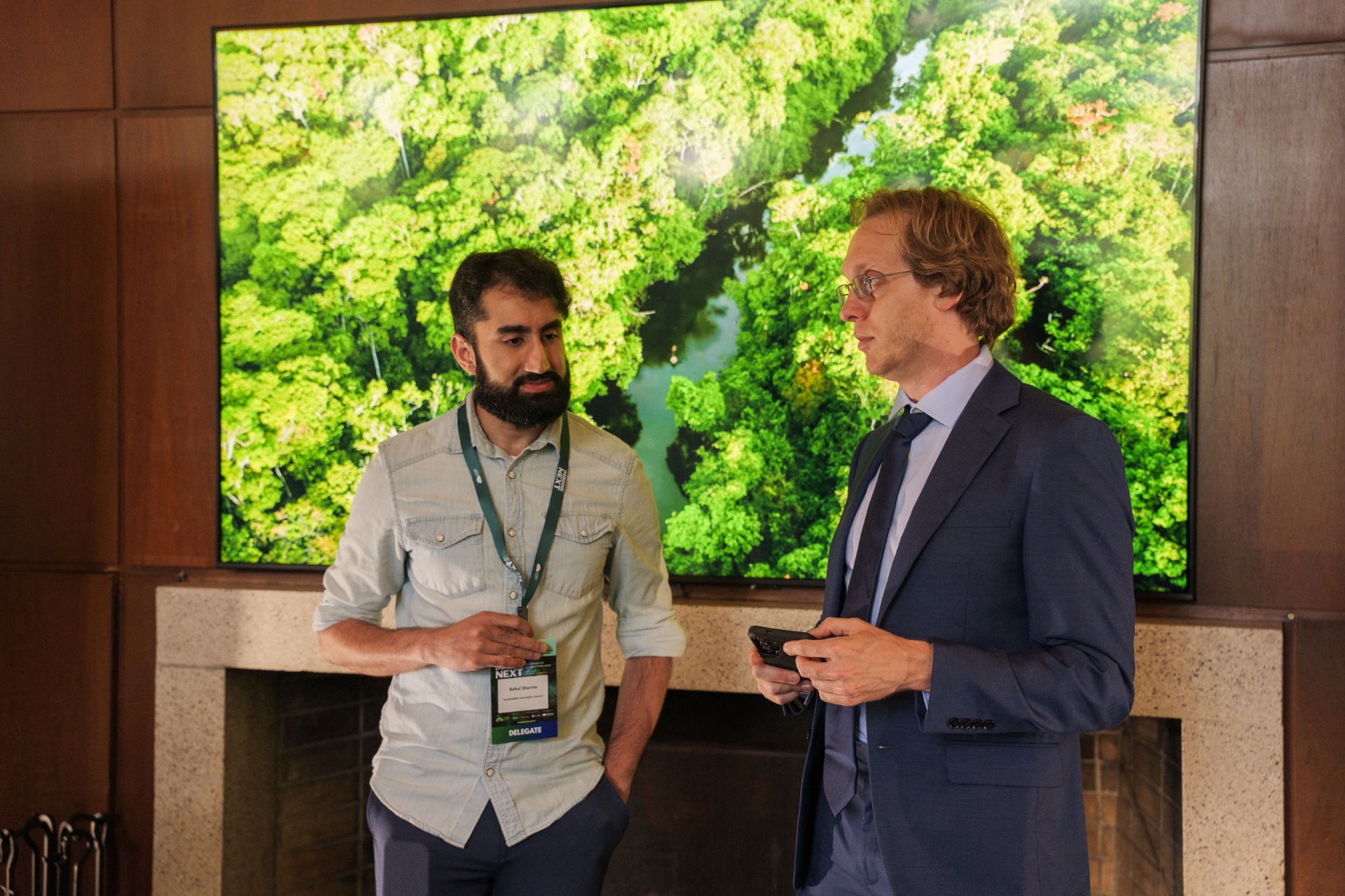 Delegates in conversation in front of Amazon screen