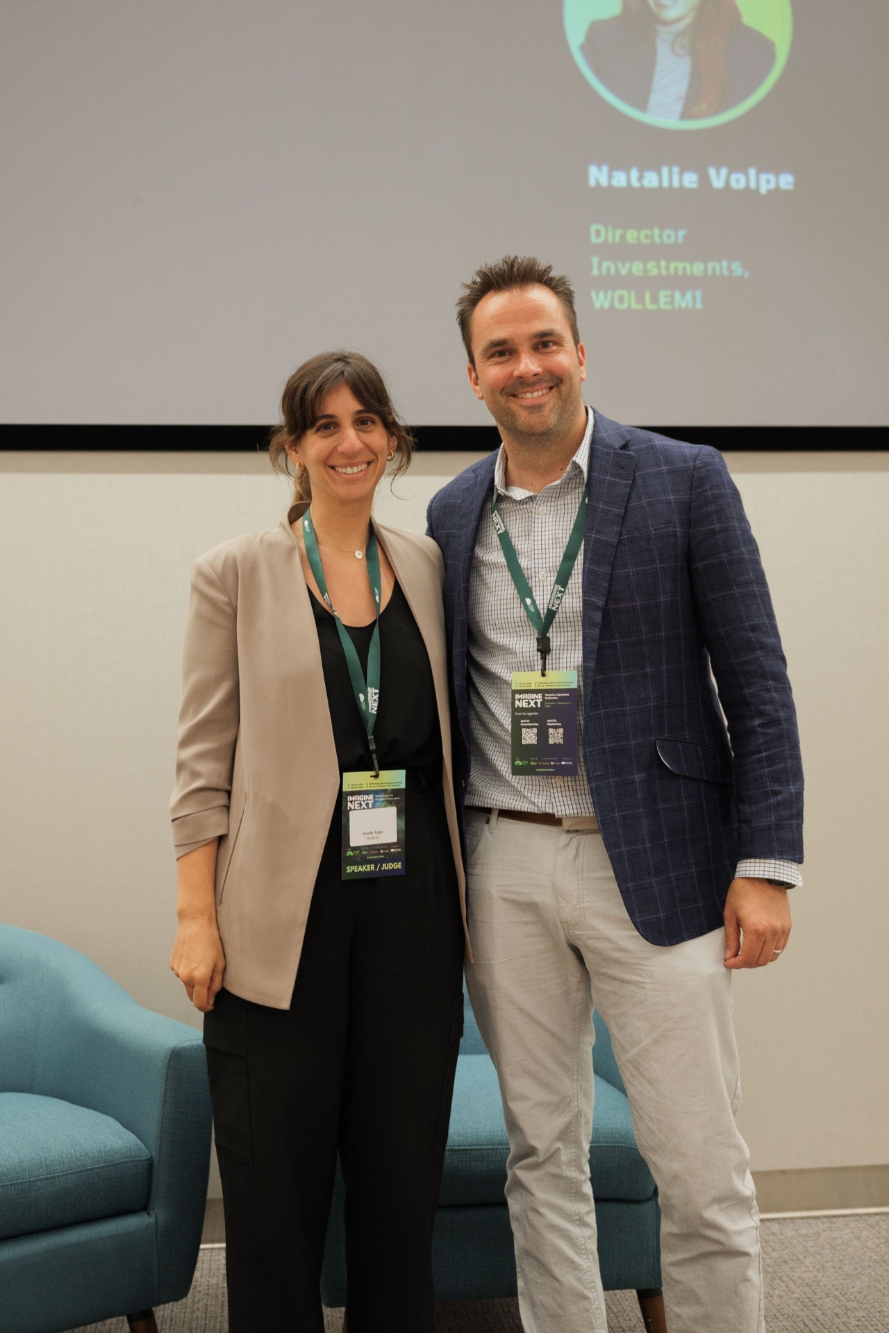 Natalie Volpe, Director of Investments at WOLLEMI, with a male Imagine Next juror beneath her speaker slide on the Capital Day stage at UC Law SF