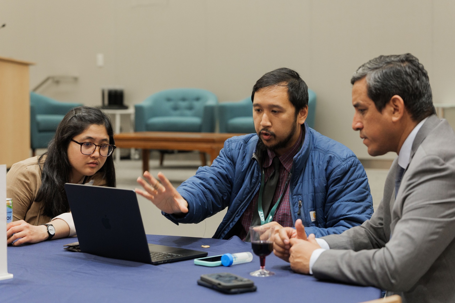Three delegates gathered around a laptop in animated discussion during the Capital Day Curated Capital Matchmaking Sessions at UC Law SF
